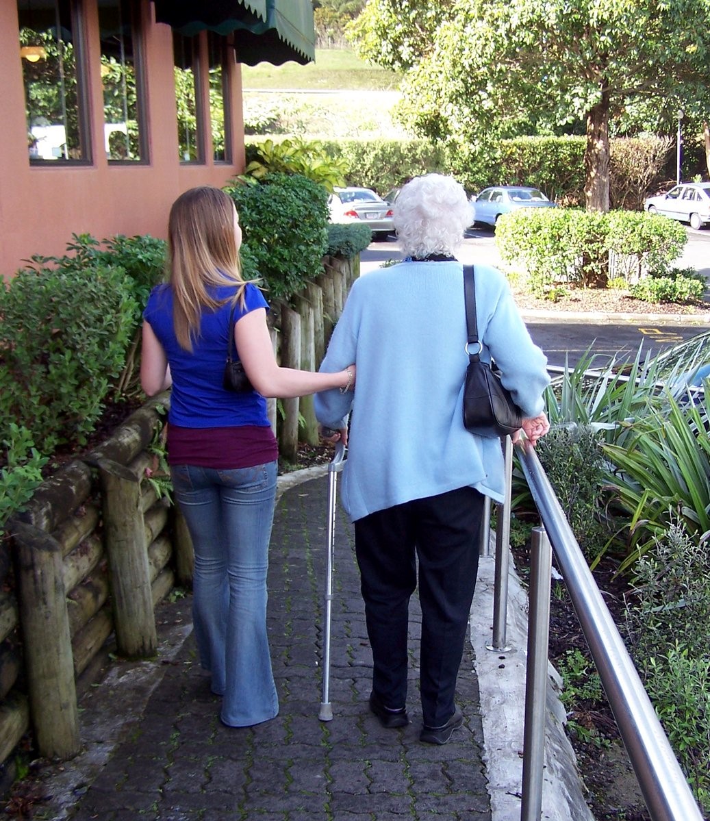 young woman helping senior down a ramp