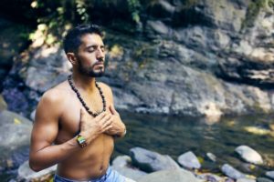 Man meditating by stream